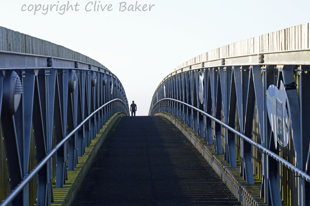 man walking over footbridge