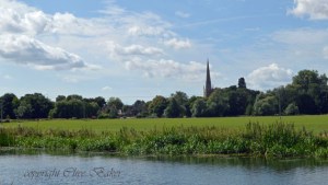 River with green fields and a church spire 